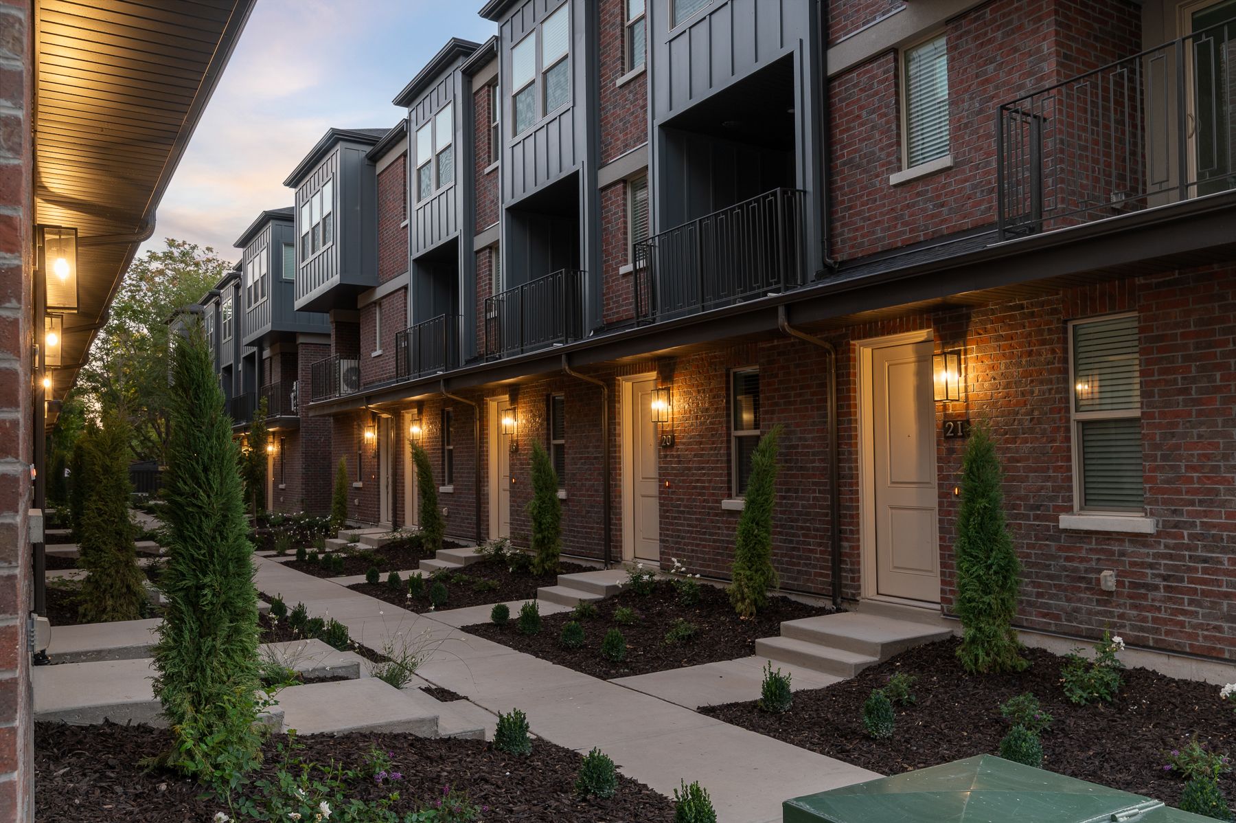 Walkway lined with lit townhome entrances at Liberty Wells